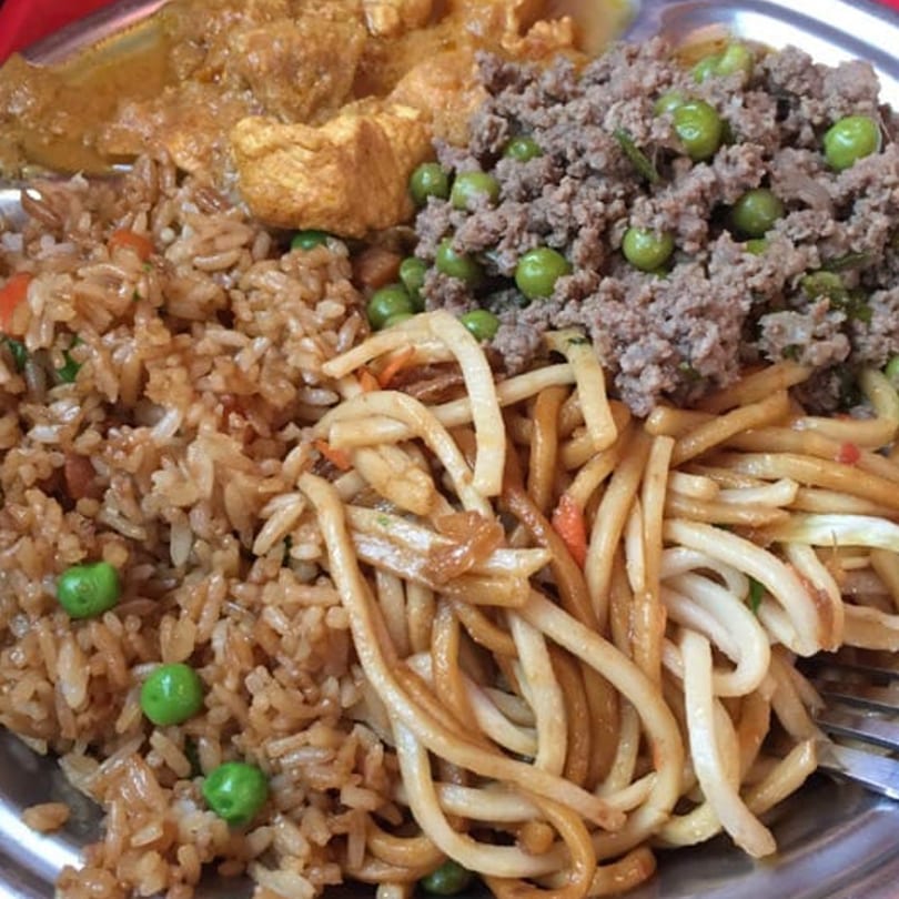 A plate of Tibetan Kitchen's fried rice, noodles, curried tofu, and ground meat with peas.