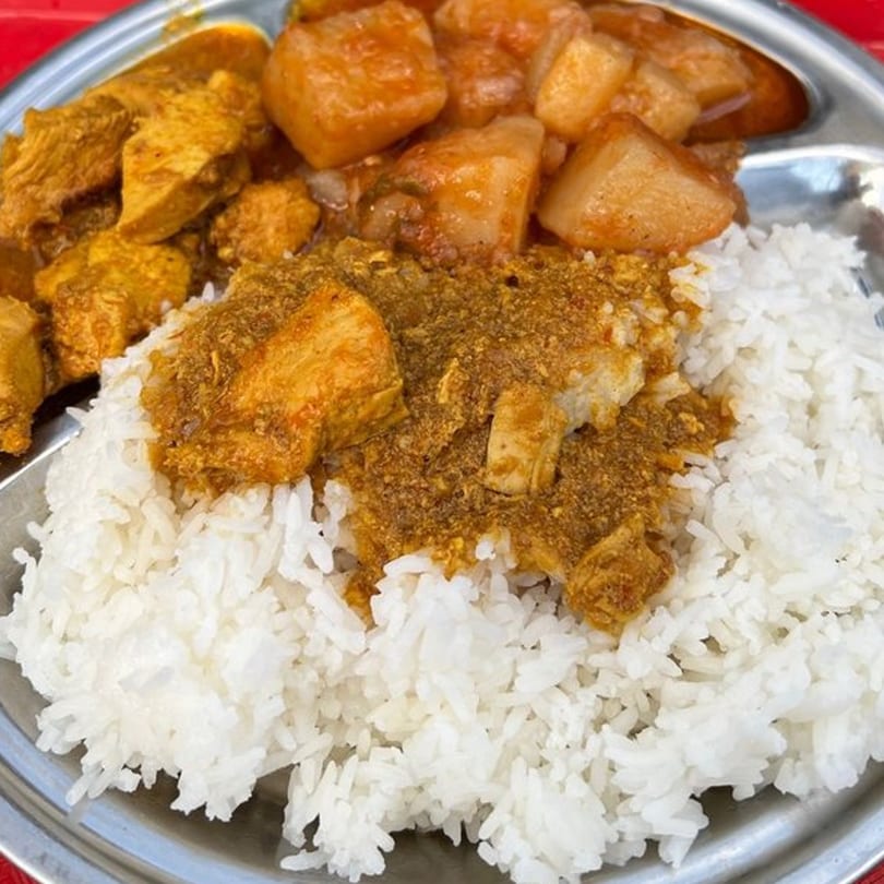 A metal plate with white rice, chicken curry, and potato curry from Tibet Kitchen.